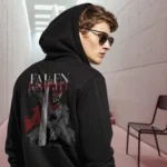 A male model with his back turned wearing a black Dark Fantasy hoodie featuring a fallen knight sitting still, sword plunged into the ground, with a visibly large hole in his armor