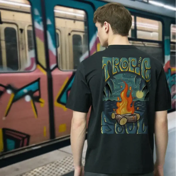 A male model with his back turned wearing a black tropic soul tshirt featuring the Moon Fire and night sky over the sea graphic.