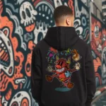 A male model with his back turned wearing a black Easy Days hoodie featuring a cow juggling spices and ingredients for an exotic soup with a bandaid on its crotch.