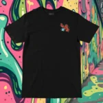 Front view of black tshirt featuring a cow juggling spices and ingredients for an exotic soup with a bandaid on its crotch.