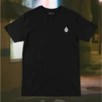 Front view of black shirt featuring a grotesque creature, seemingly being born, wriggling from its attachment