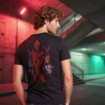 A male model with his back turned wearing a black Dark Fantasy shirt featuring a demonic red being, several hands floating and holding different signs with a single heart beating, the pentagram behind silent