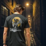 A male model with his back turned wearing a black Manifesto shirt featuring a winged horned woman sat down, holding a dagger with an evil grin