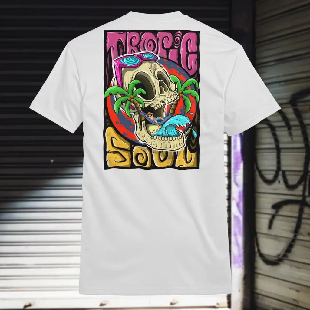 Back view of white Tropic Soul tshirt displaying a man relaxing on a hammock tied to the Skull Island's palm trees next to a giant wave rear graphic placement.