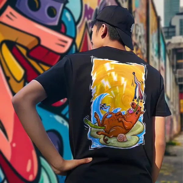 A male model with his back turned wearing a black Easy Days tshirt featuring a roasted pig skewered by a bamboo stick, lying underneath an umbrella taking cover from the sun.