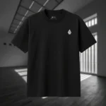 Front view of black tshirt featuring a gray winged creature of dark, visibly hanged by ropes, opening its stomach with its unseen face